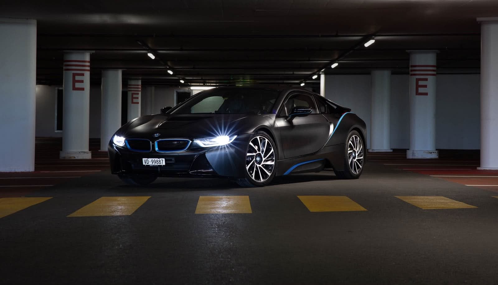 BMW i8 noire, phares allumés, dans un parking souterrain