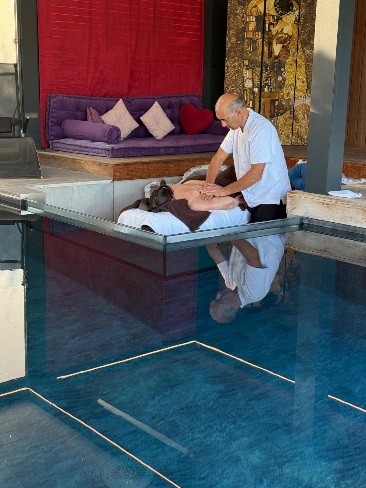 Le coin détente de Secret Paradise : banquette violette, paravent inspiré de Klimt et tenture rouge, au bord de l'eau