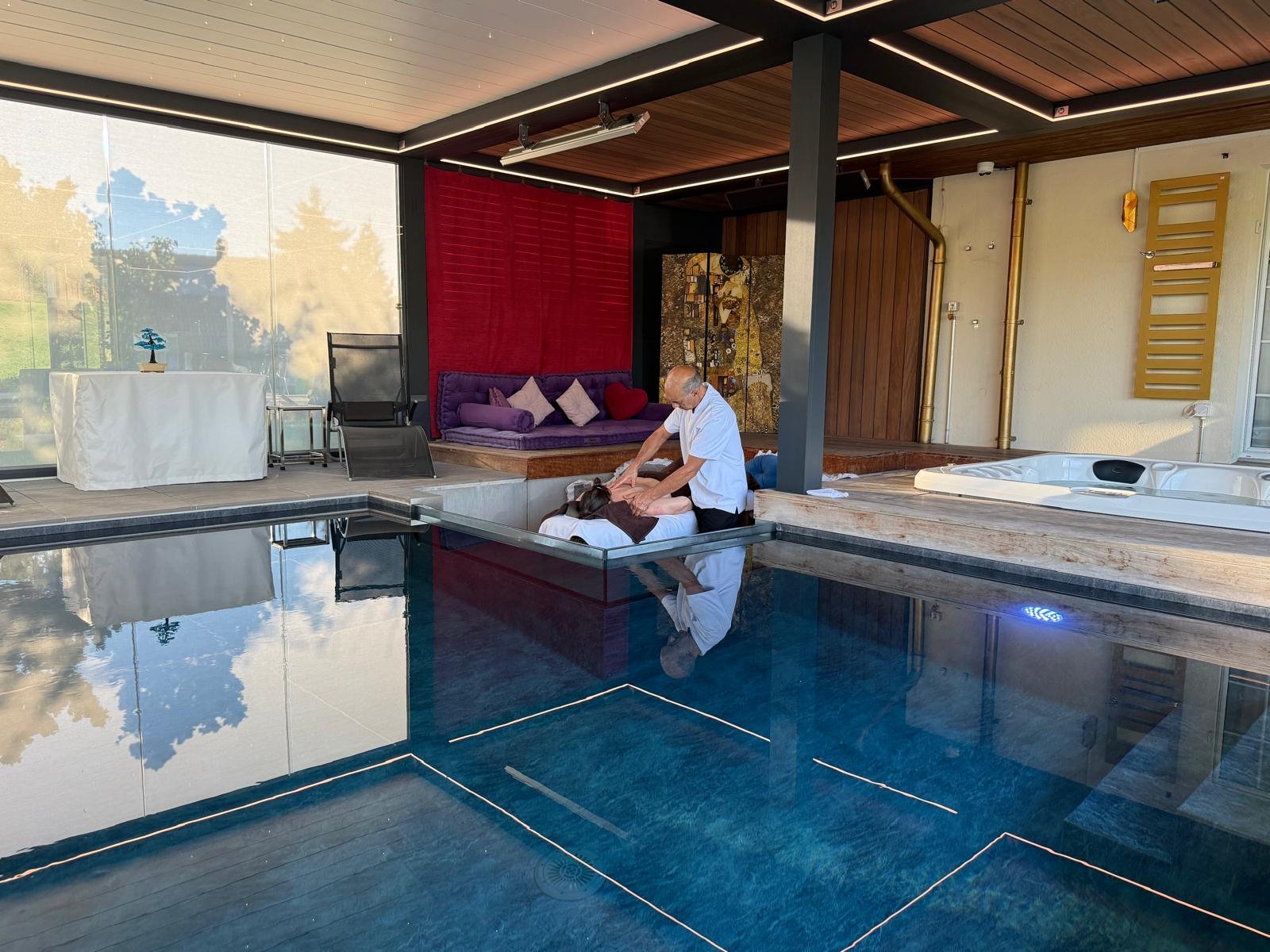 Vue large de l'espace massage de Secret Paradise, entre la piscine et le jacuzzi, sous la pergola en bois
